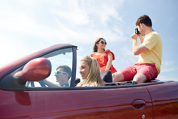 Image showing happy friends with camera driving in cabriolet car