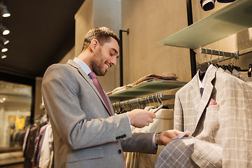 Image showing man in suit with smartphone at clothing store