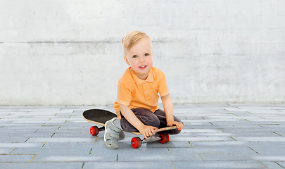 Image showing happy little boy sitting on skateboard