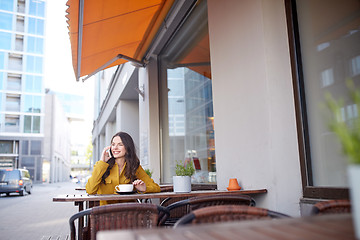 Image showing happy woman calling on smartphone at city cafe