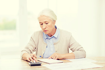 Image showing senior woman with papers and calculator at home
