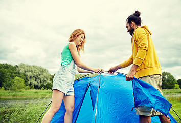 Image showing happy couple setting up tent outdoors