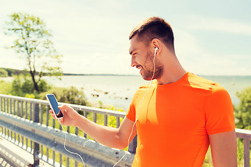 Image showing smiling young man with smartphone and earphones