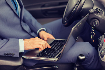 Image showing close up of young man with laptop driving car