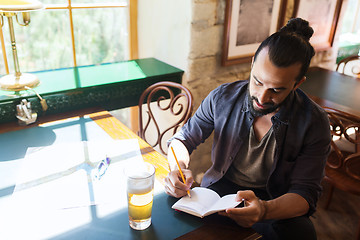 Image showing man with beer writing to notebook at bar or pub