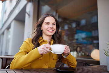 Image showing happy woman drinking cocoa at city street cafe