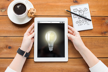 Image showing close up of woman with tablet pc on wooden table