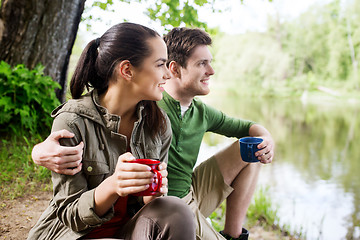 Image showing happy couple with cups drinking in nature