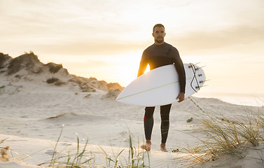 Image showing A surfer with his surfboard 