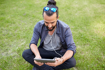 Image showing man with earphones and smartphone sitting on grass