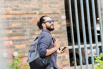 Image showing man with earphones and smartphone walking in city