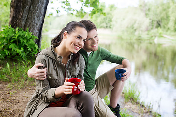 Image showing happy couple with cups drinking in nature