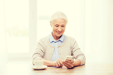 Image showing senior woman with smartphone texting at home