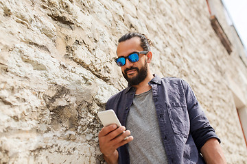 Image showing man texting message on smartphone at stone wall
