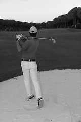 Image showing golfer hitting a sand bunker shot on sunset