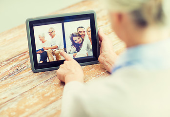 Image showing senior woman with family photo on tablet pc screen