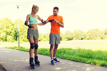 Image showing happy couple with roller skates riding outdoors