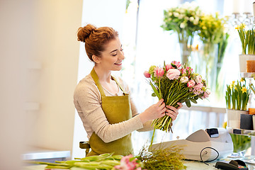 Image showing smiling florist woman making bunch at flower shop