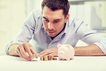 Image showing businessman with piggy bank and coins at office