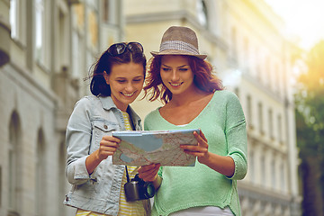 Image showing smiling teenage girls with map and camera outdoors