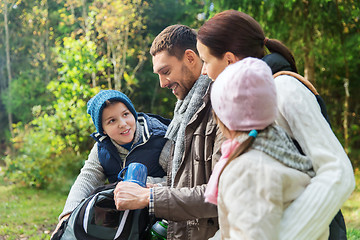 Image showing happy family with backpacks and thermos at camp