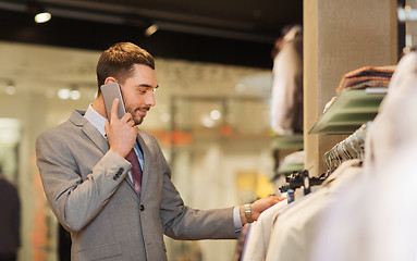 Image showing happy man calling on smartphone at clothing store