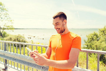 Image showing smiling young man with smartphone and earphones