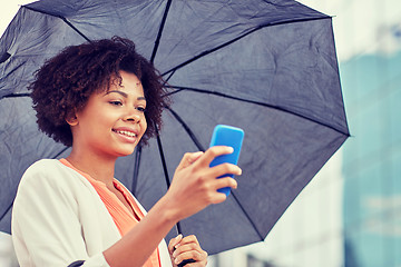 Image showing businesswoman with umbrella texting on smartphone