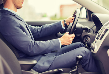 Image showing close up of young man in suit driving car