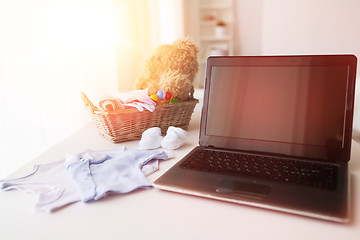 Image showing close up of baby clothes, toys and laptop at home