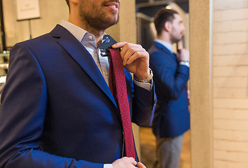 Image showing close up of man trying tie on at mirror