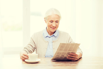 Image showing senior woman with coffee reading newspaper at home