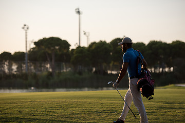 Image showing golfer  walking and carrying golf  bag at beautiful sunset