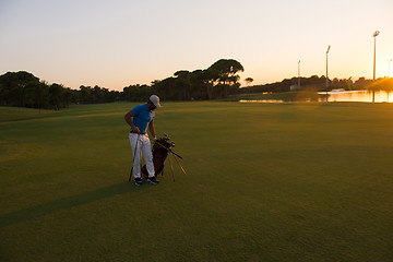 Image showing golfer  walking and carrying golf  bag at beautiful sunset