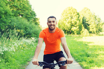 Image showing happy young man riding bicycle outdoors