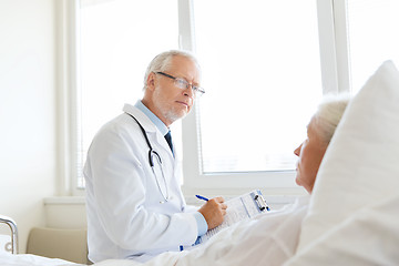 Image showing senior woman and doctor with clipboard at hospital