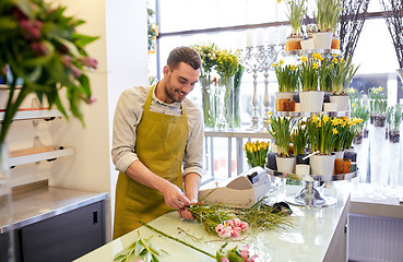 Image showing smiling florist man making bunch at flower shop