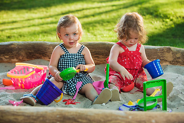 Image showing The two little baby girls playing toys in sand