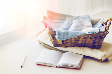 Image showing close up of baby clothes for newborn and notebook