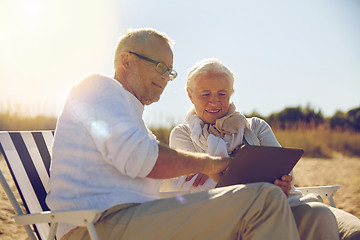 Image showing happy senior couple with tablet pc on summer beach