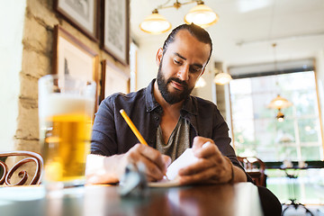 Image showing man with beer writing to notebook at bar or pub