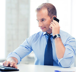 Image showing smiling businessman with smartphone in office