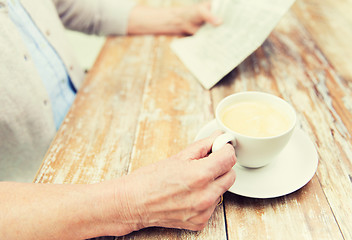 Image showing senior woman with coffee reading newspaper at home