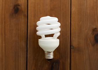 Image showing close up of energy saving lighting bulb on wood