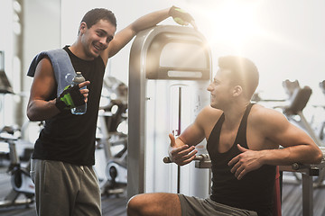 Image showing smiling men exercising on gym machine