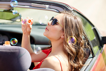 Image showing woman blowing bubbles in convertible car