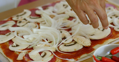 Image showing Woman placing onion on a homemade pizza