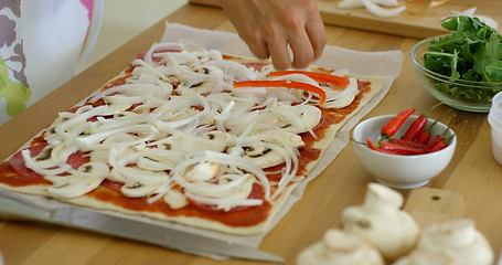 Image showing Woman placing onion on a homemade pizza