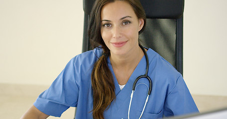 Image showing Young female physician places one hand on her face