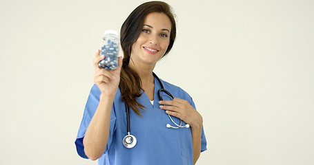 Image showing Young brown haired doctor in scrubs holds bottle